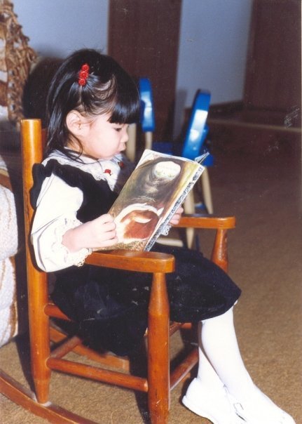 A young child reading a well-worn copy of "Home for a Bunny" in a rocking chair