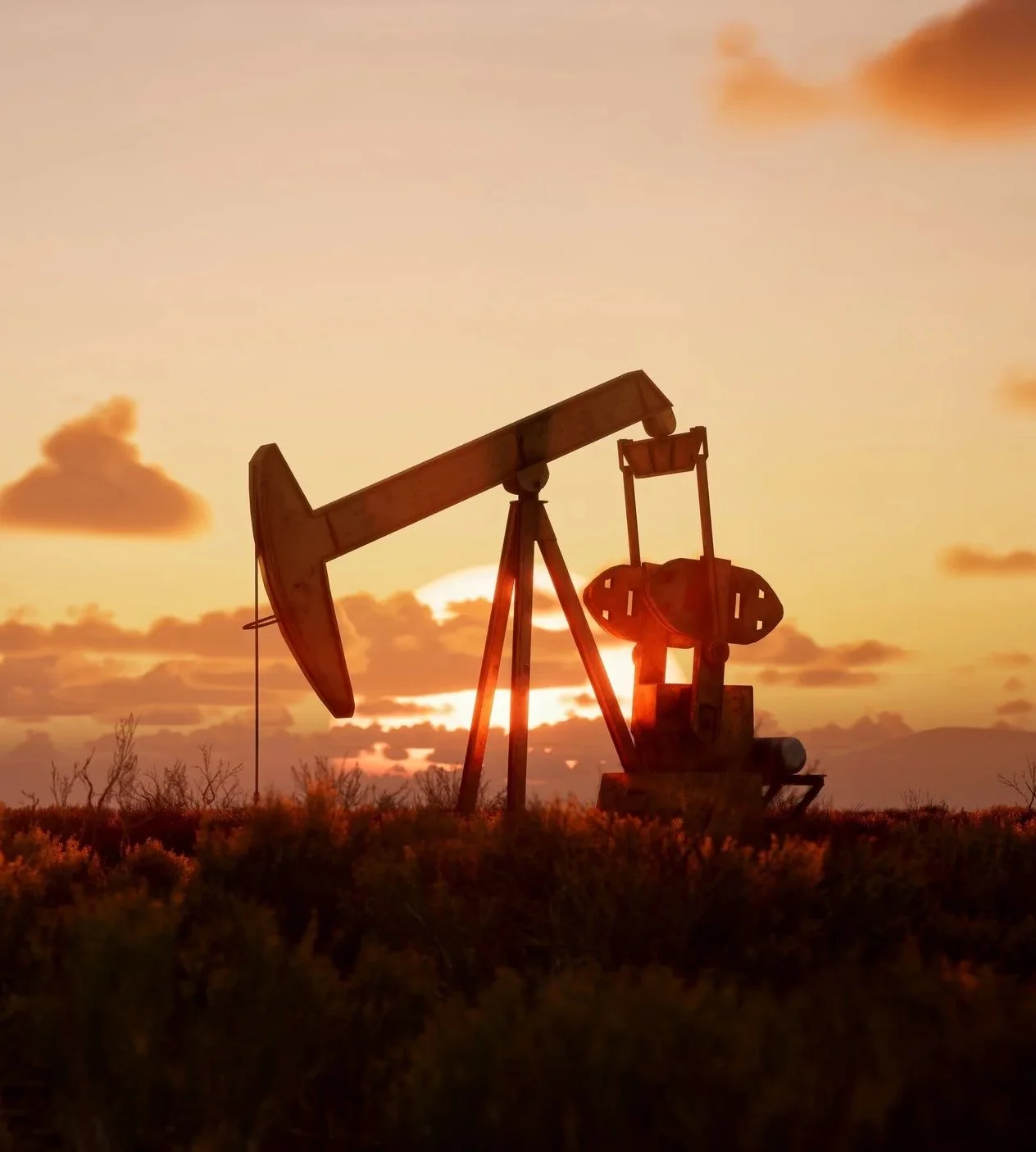Silhouette of an industrial oil pump backlit by a sunset.