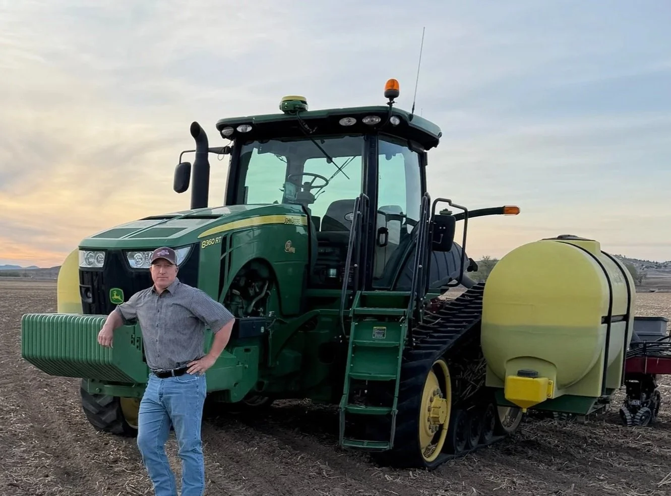 Joe Speckner, candidate for Wyoming House District 5, posing next to a large John Deere tractor.
