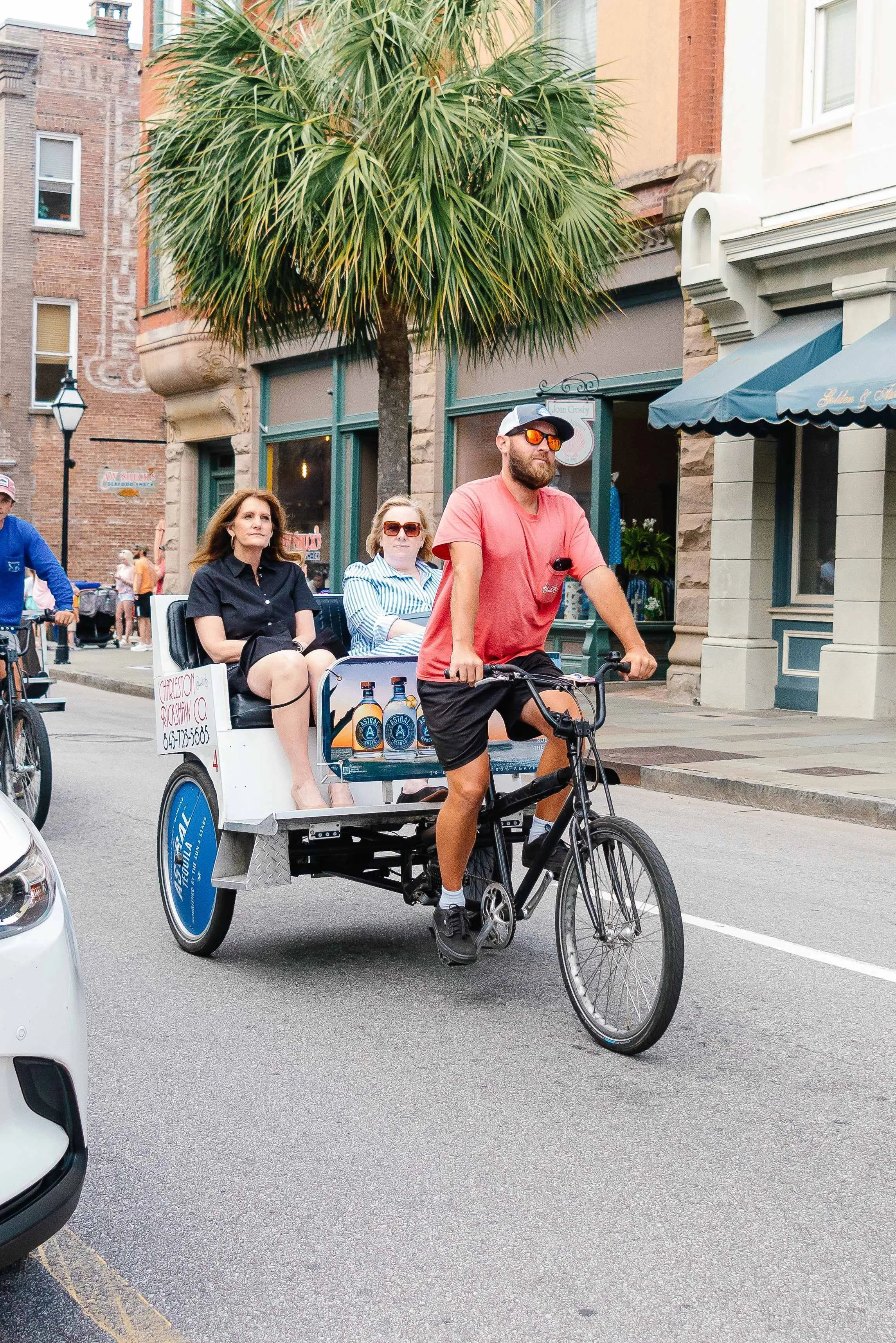 Charleston Rickshaw driver giving two passengers an open-air ride through downtown Charleston