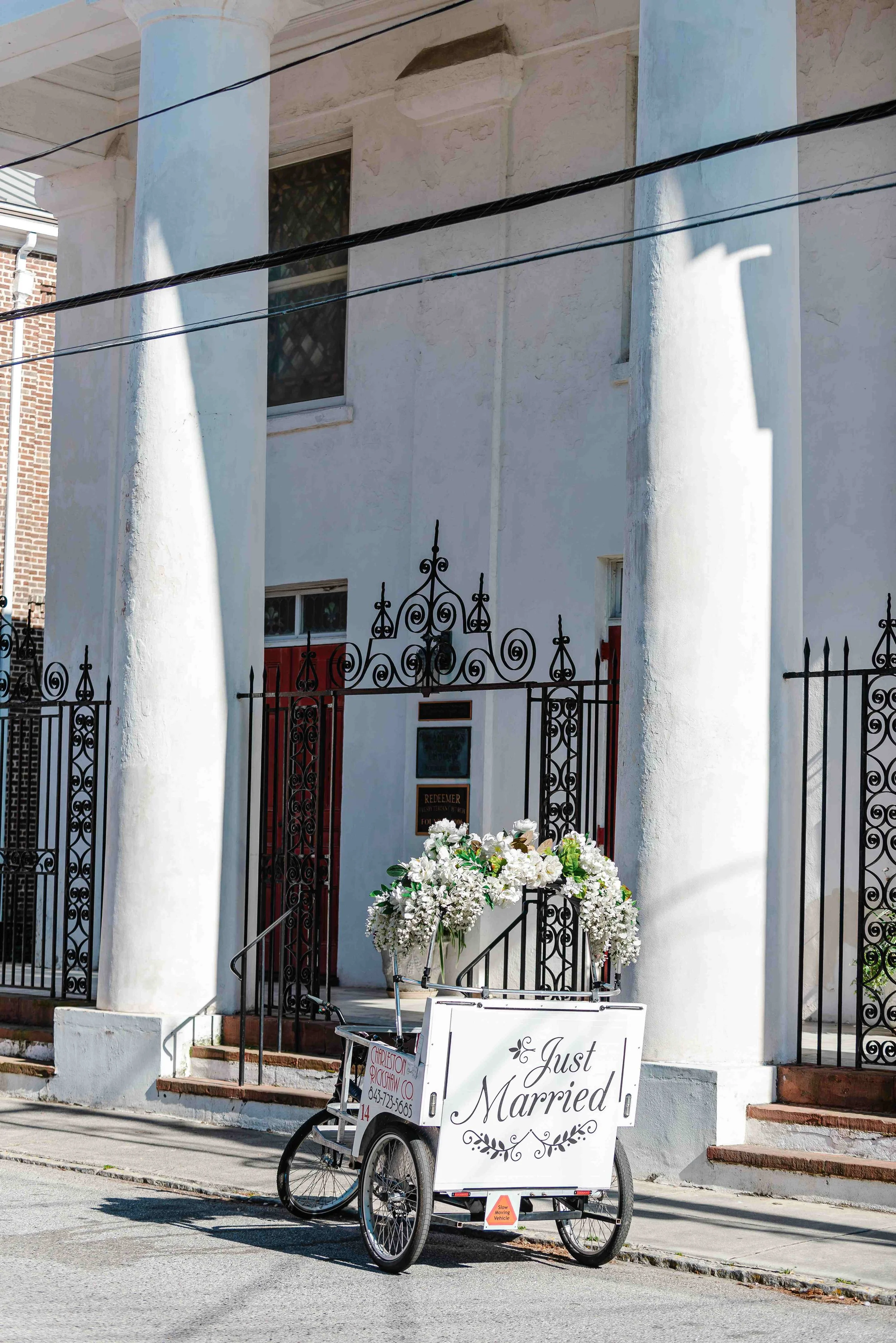 Decorated Charleston Rickshaw wedding bike with 'Just Married' sign for a downtown Charleston send-off
