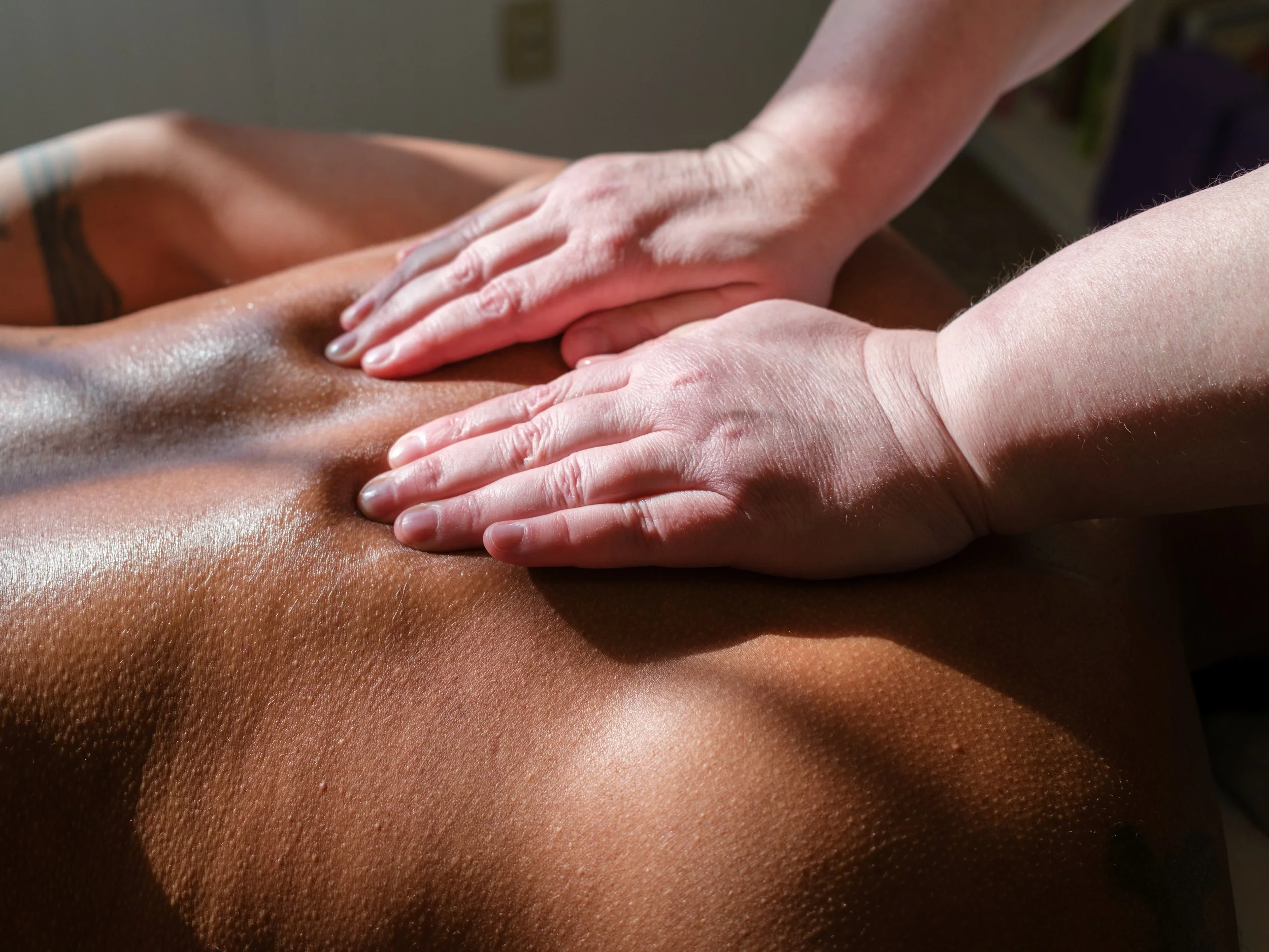 Close-up of a person receiving a back massage, with hands applying pressure to the back.