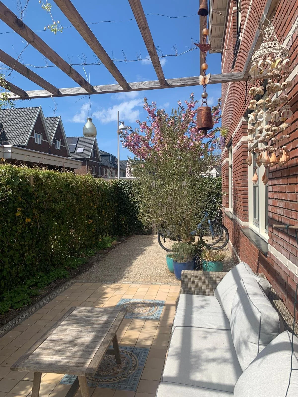 April 2026: Door het gebruik van halfverharding, de motieftegels en herplaatsing olijfboom zorgen de aanpassingen  voor een warm geheel en zijn de fietsen 'weggewerkt'. .  