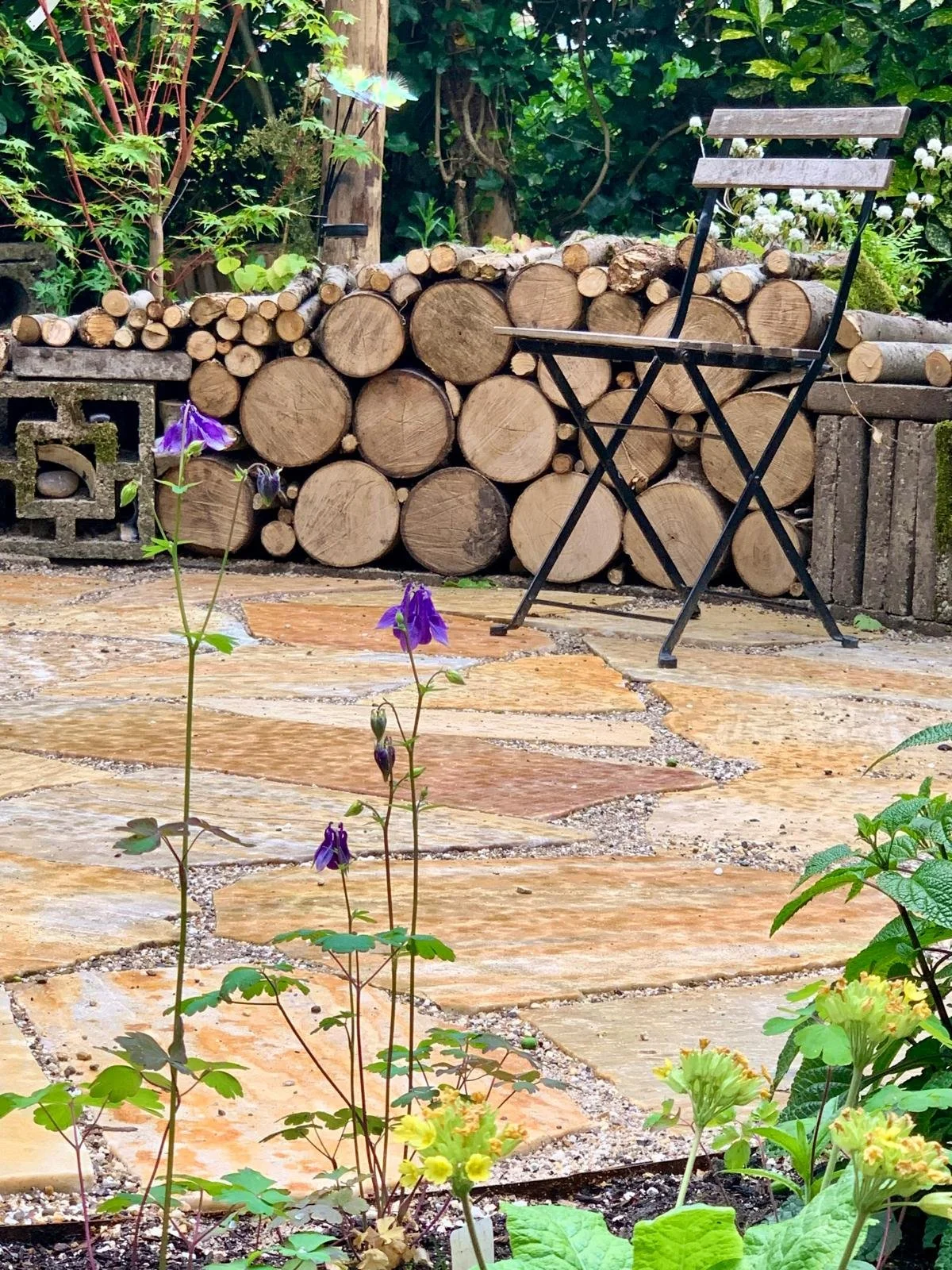 Flagstones Brasil Yellow XXL op de plek van de trampoline, gevoegd met halfverharding Achterhoeks padvast, zodat de regen zijn weg naar beneden weet te vinden.  En zitkuil effect gecreëerd door tuin verder op te hogen en stammenwand te maken van besc