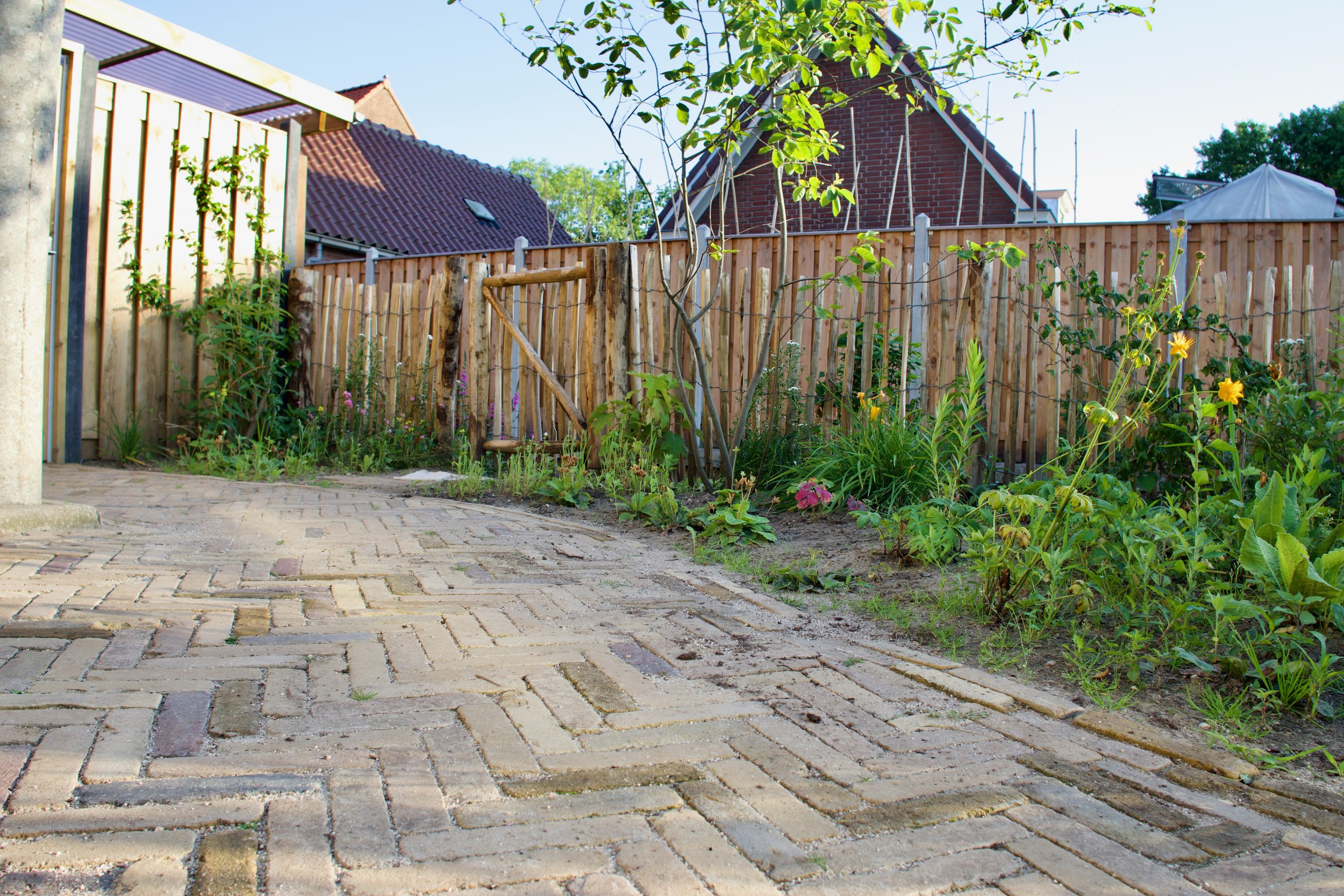 Een halfopen overkapping aan de zijkant van het huis voor extra bergruimte.  Voor de beplanting is aan alle lagen gedacht.  