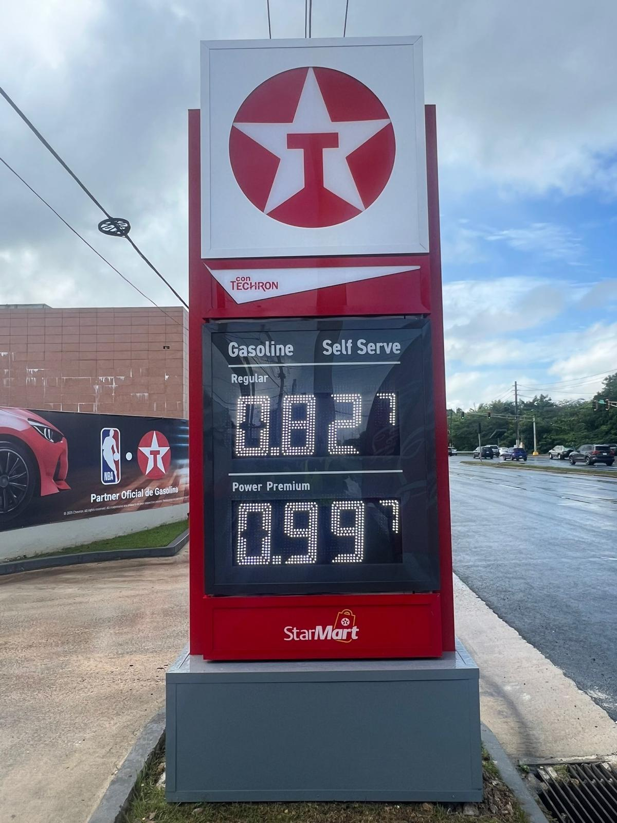 Una estación de gasolina de la marca StarMart con precios de gasolina regular a 3.82 y de Power Premium a 3.49. El cartel muestra que la gasolina regular es autoadministrada.
