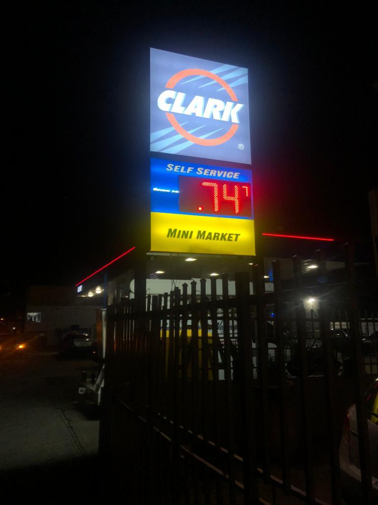 Cartel de combustible en una estación de servicio Clark mostrando el precio de 0.74 por galón y también anuncia un mini mercado y auto servicio.