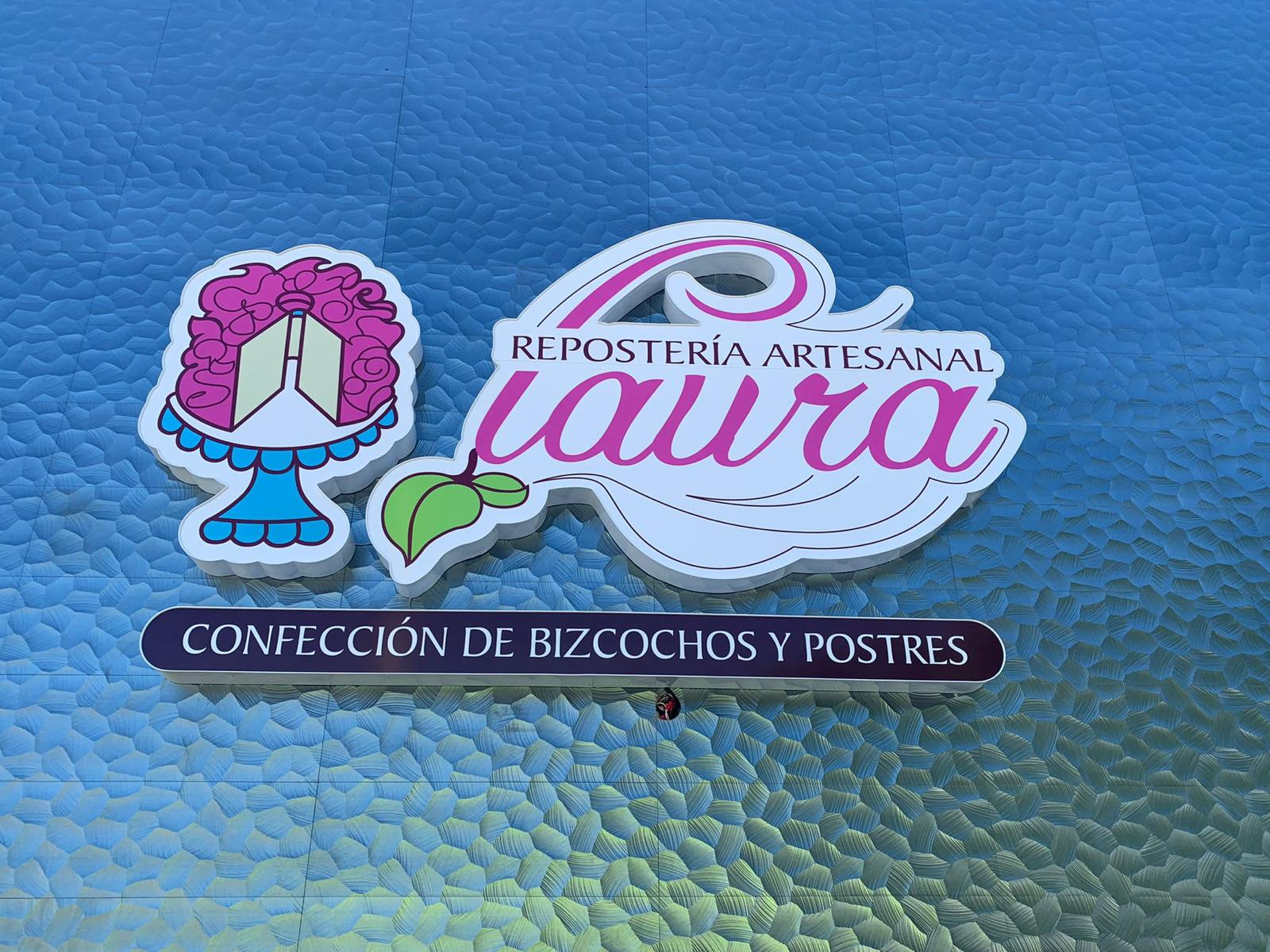 Logotipo de una panadería artesanal llamada Laura, con un diseño de taza y hoja, y un fondo de color azul y letras en rosa y morado.