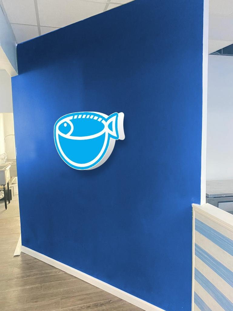 Signo azul con dibujo de pez, posiblemente en un entorno de pescadería o mariscos.