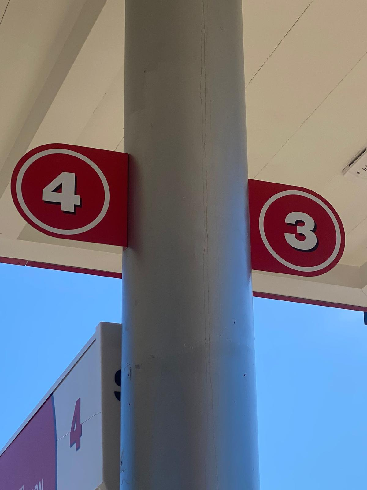 Señales de números 4 y 3 en lugares diferentes en un poste en una estación de autobuses o similar.