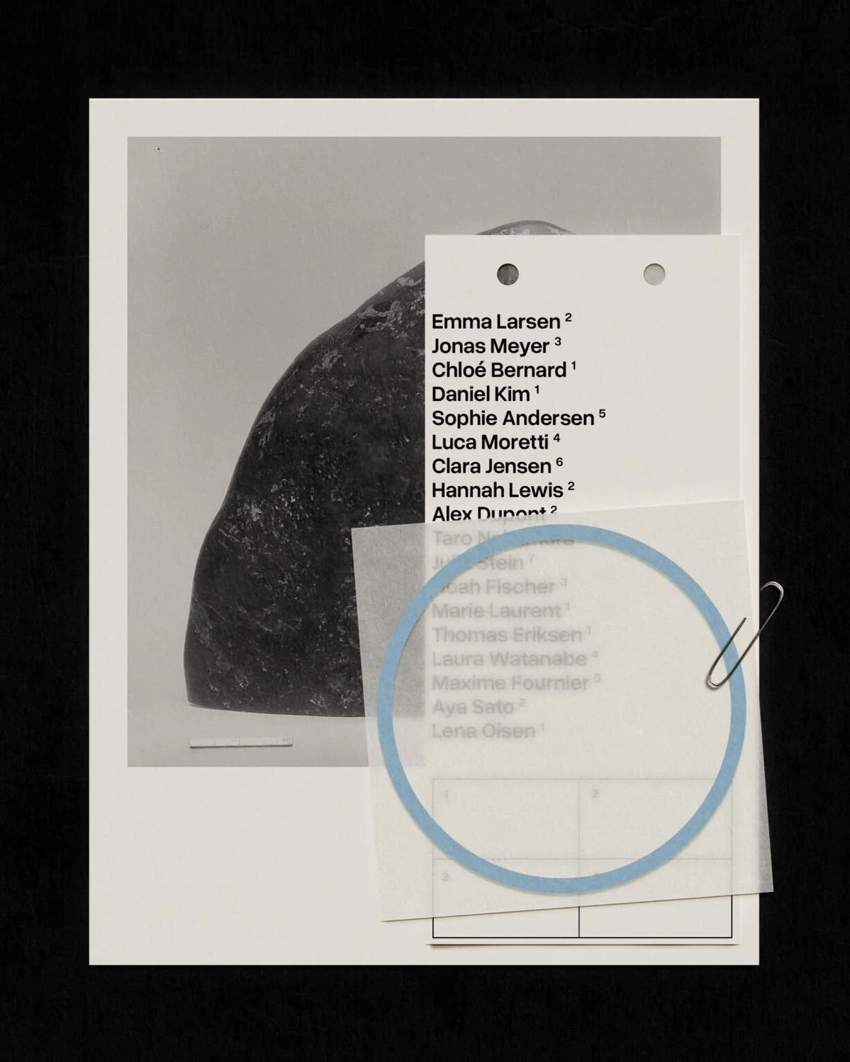 A printed sheet with a list of names, a black and white image, and a blue circle with a paperclip attached, all on a black background.