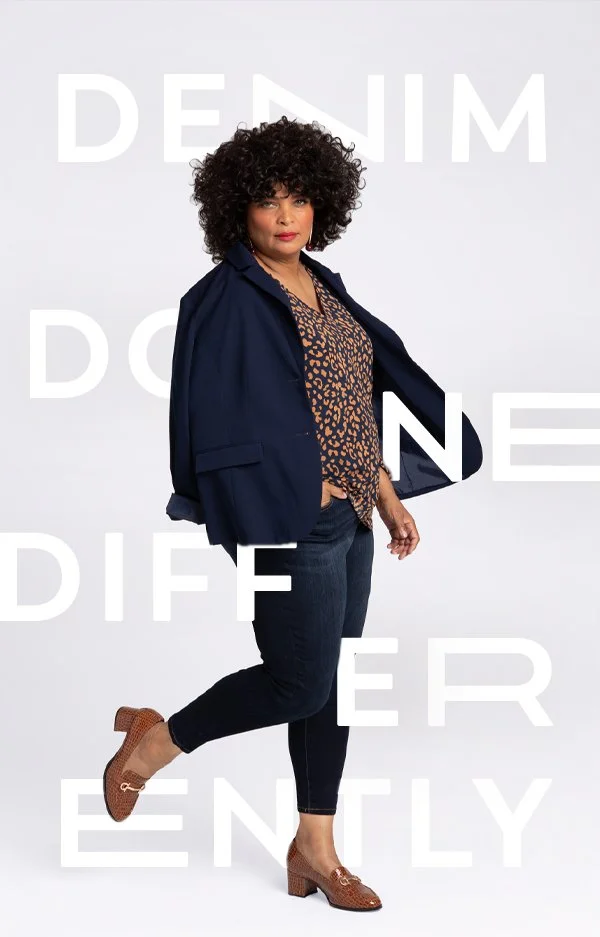 A woman with curly hair standing with one foot lifted, wearing a leopard print blouse, a navy jacket, dark jeans, and brown heels, against a white background with large, semi-transparent text.
