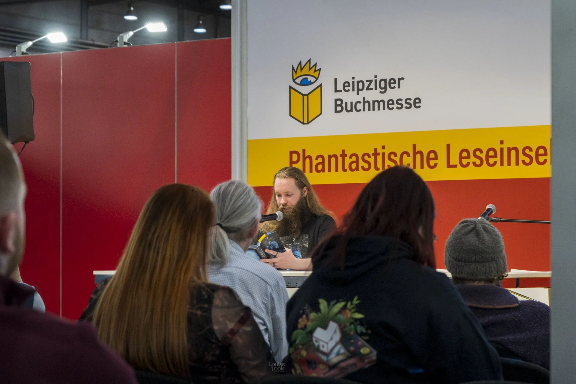 Professional indoor event photography showing a business speaker talking to an audience at a book reading live event