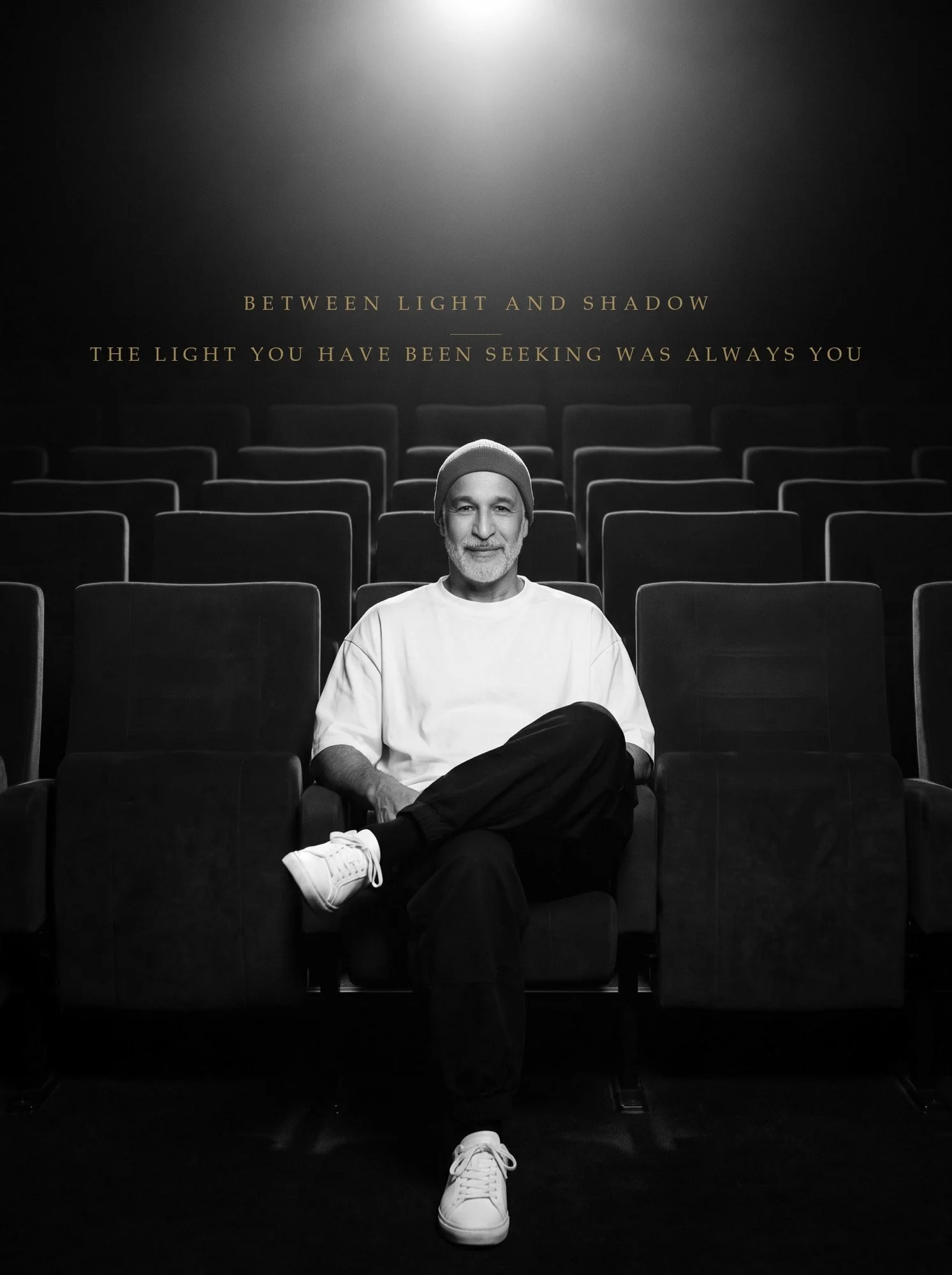 Omar Kahn seated alone in an empty cinema beneath a single light