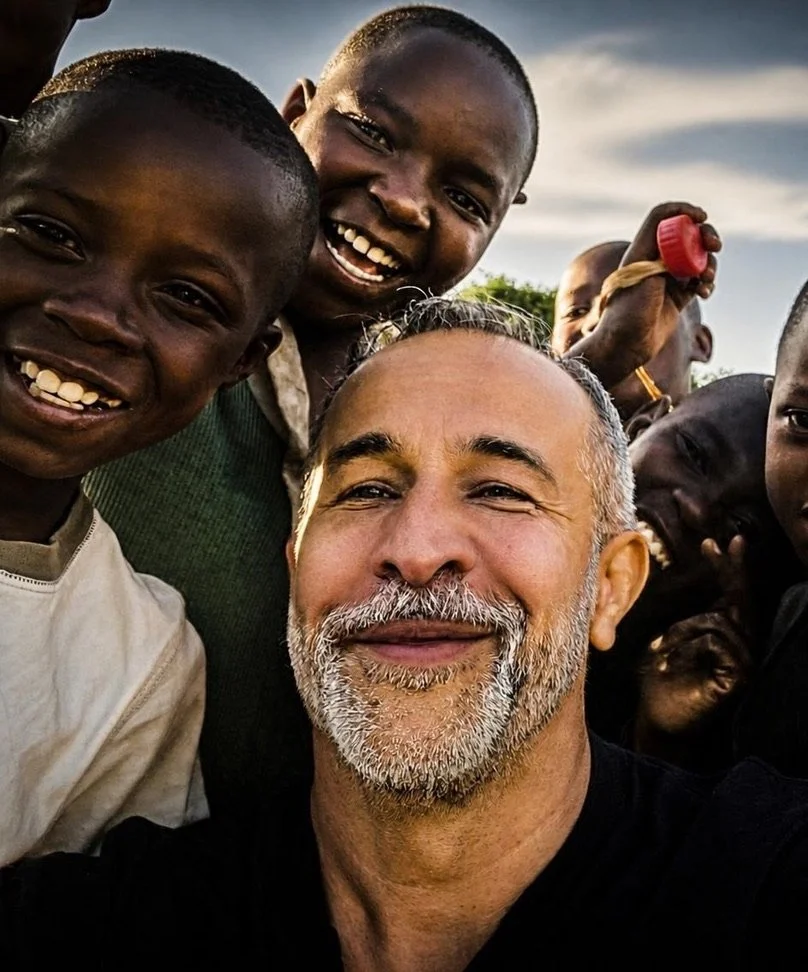 Omar Kahn smiling with a group of children