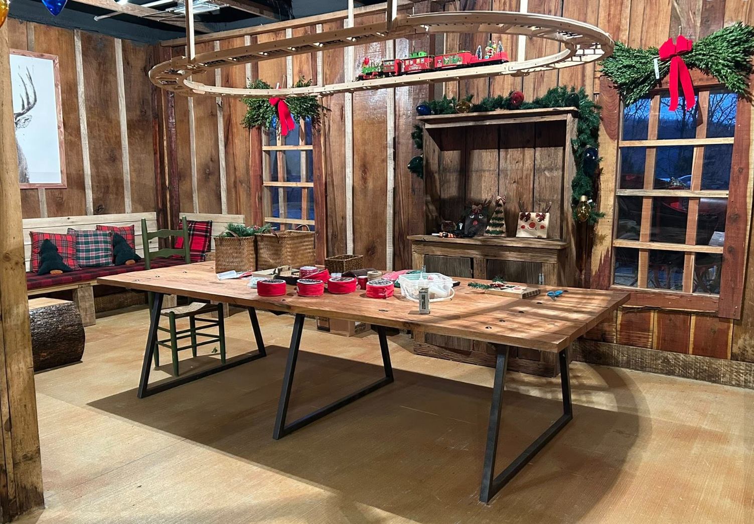 Wooden room decorated for Christmas with a large table, holiday ornaments, and garage accessories.