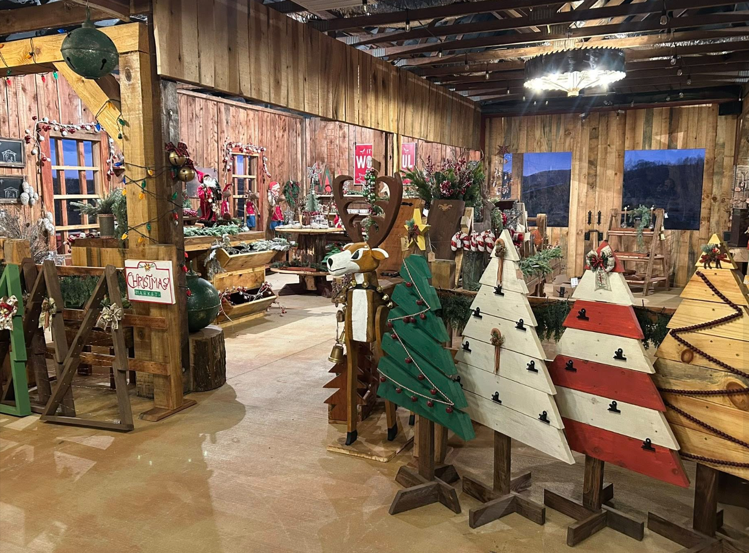 Indoor Christmas market decorated with wooden Christmas trees, ornaments, and holiday craft displays.