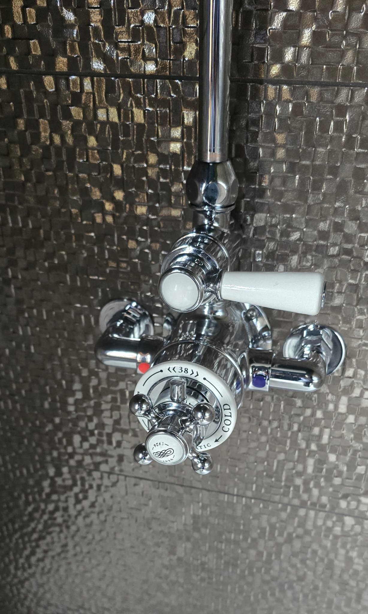 Chrome faucet with temperature control handles and a round knob with a decorative design. Installed by Chris Murphy Plumbing and Heating 2026
