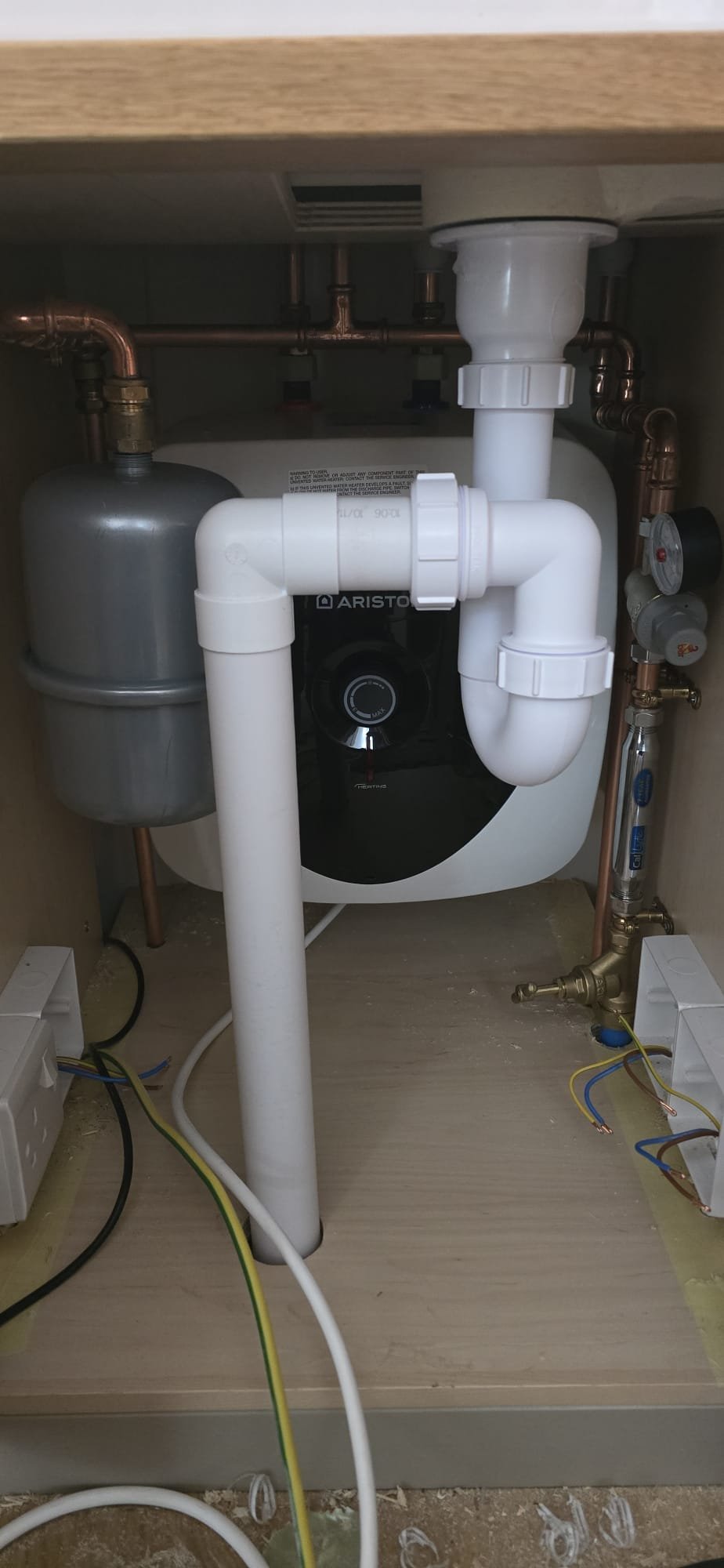 Plumbing pipes and a water filtration system installed under a kitchen sink.