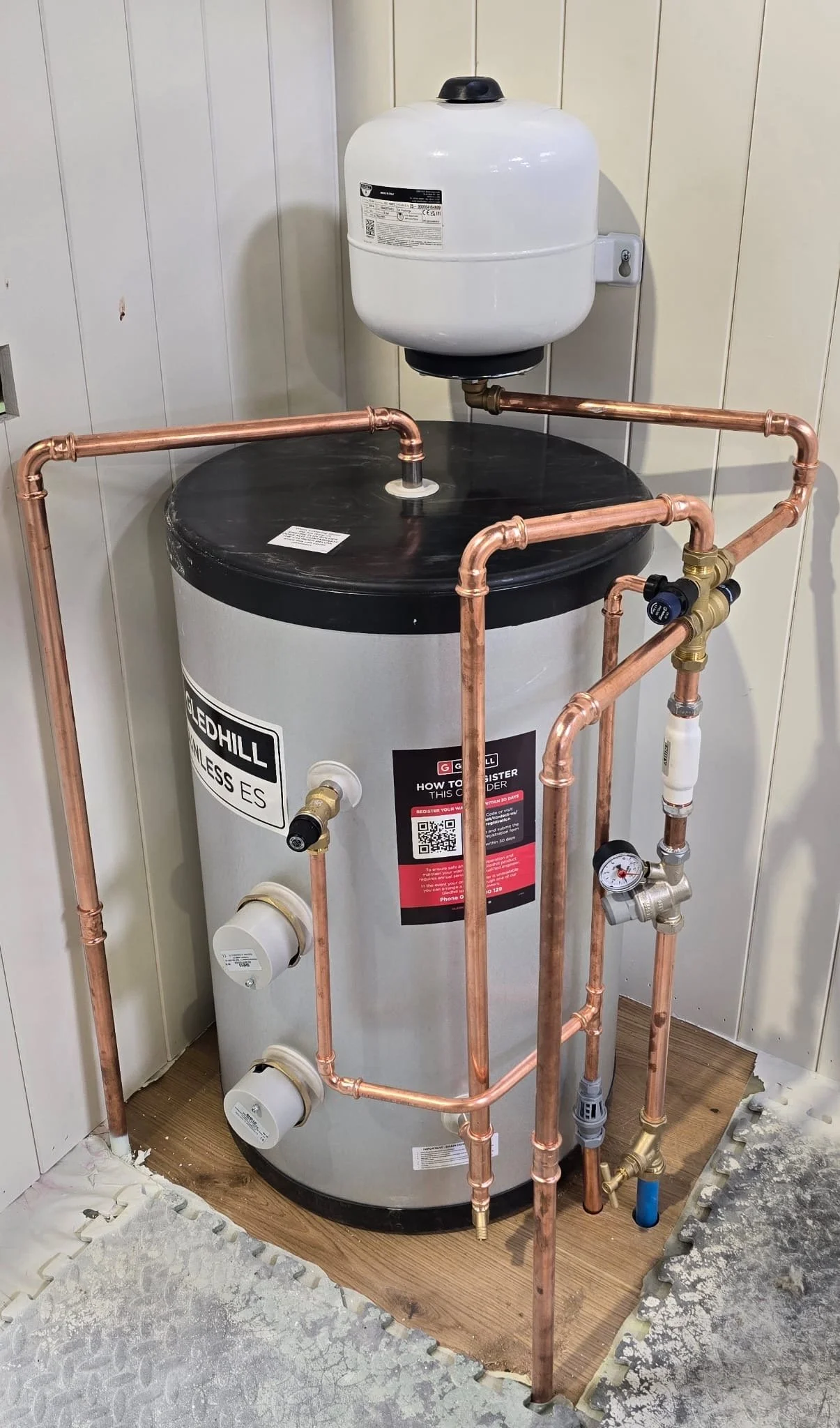 A water heater connected to copper pipes. Installed by Chris Murphy Plumbing and Heating 2026