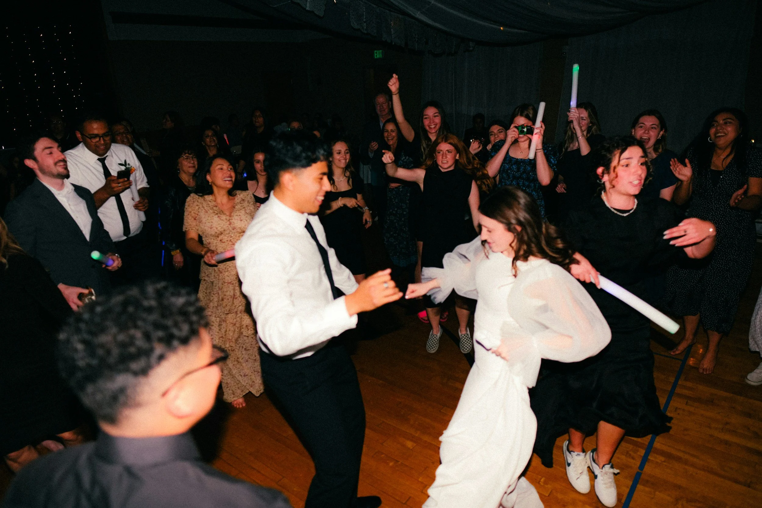 A group of people dancing and celebrating at a party or event in a dimly lit room.