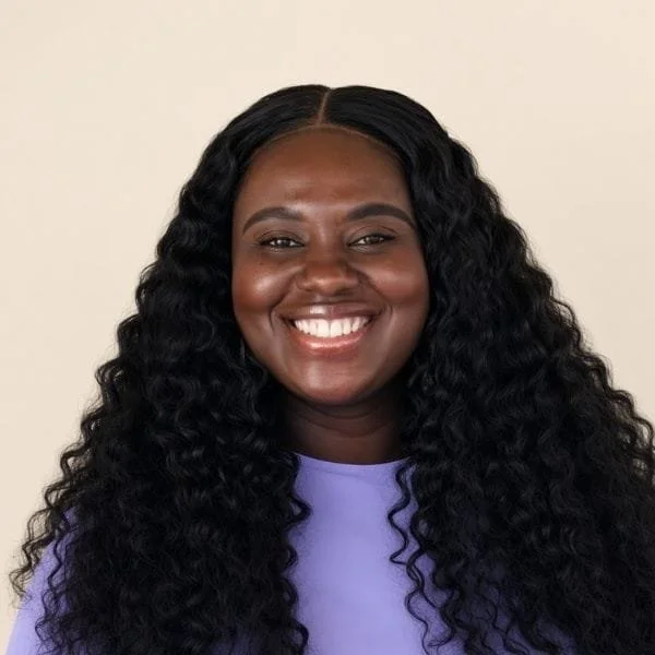 Smiling woman with long, curly black hair wearing a purple shirt.