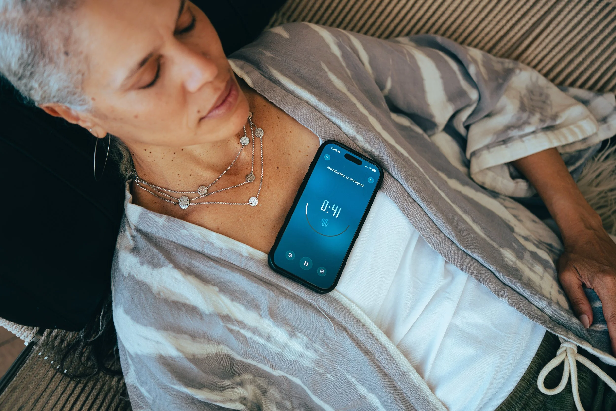 Woman laying on her back with her phone on her chest with Introduction to Biosignal and 0:41 on the screen