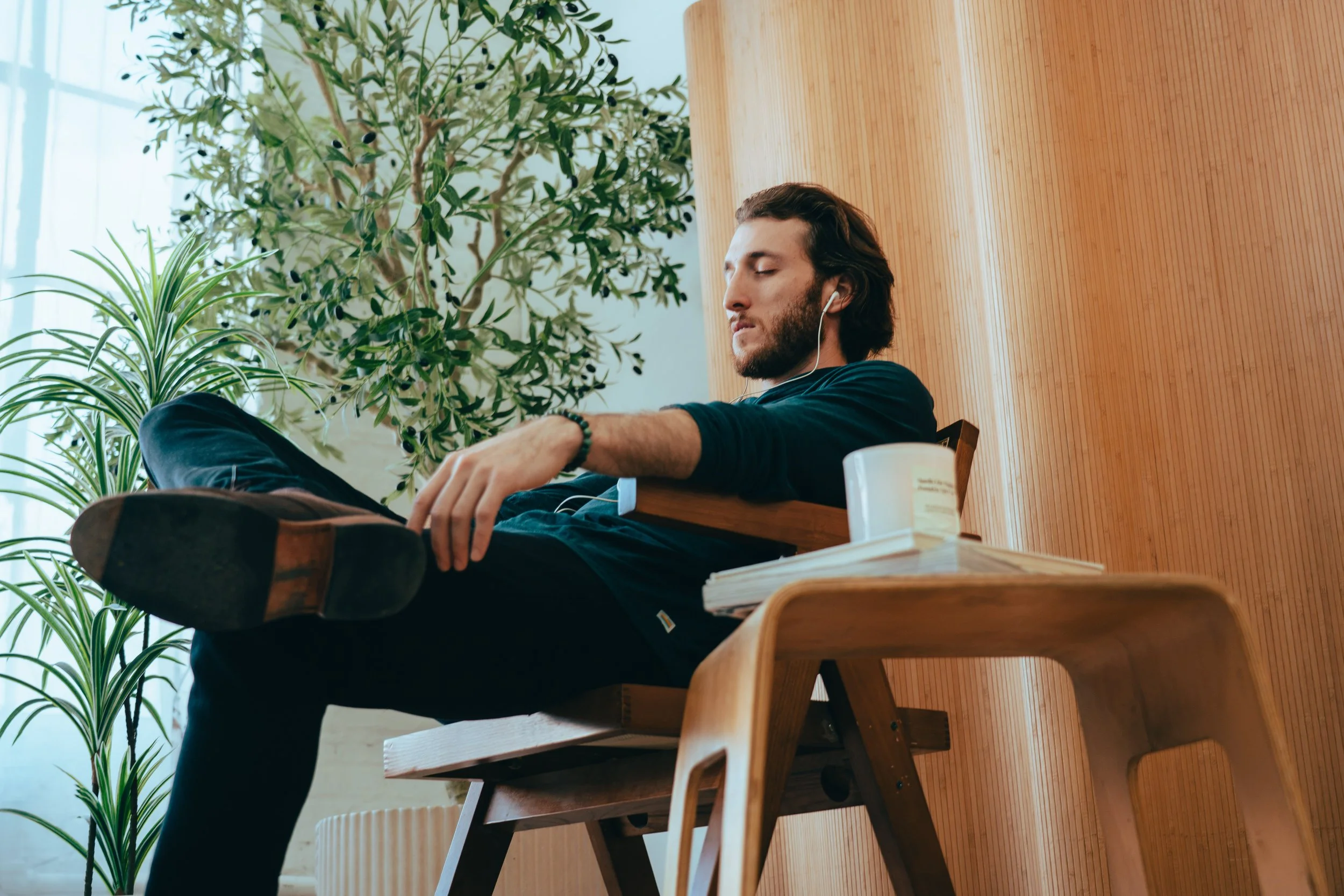 Man with a beard sitting in a chair with his eyes closed and headphones in his ears
