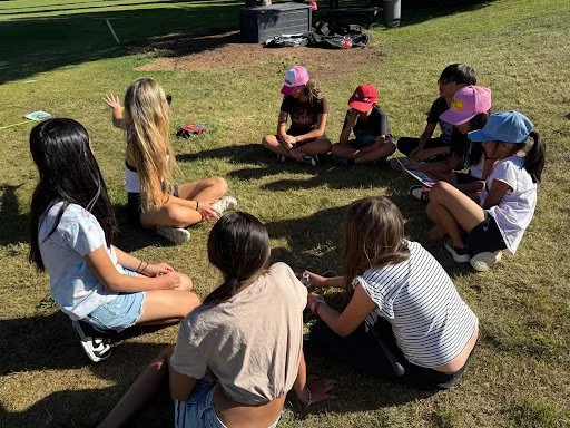 Palmer Elston leading a group discussion with NextGen Golf Academy students sitting in a circle on the grass