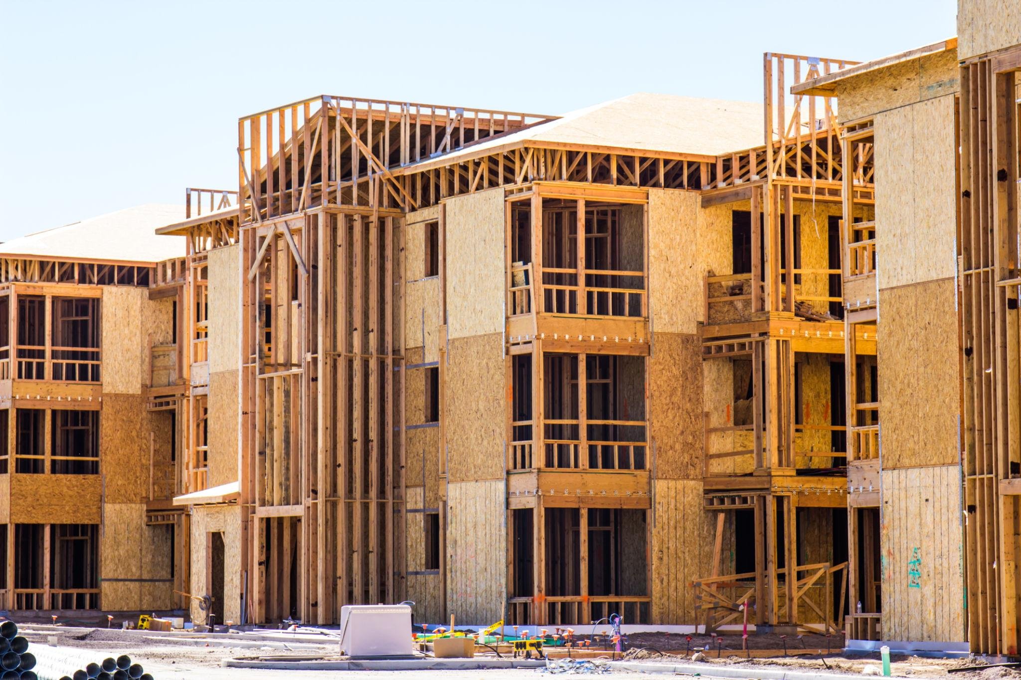 Wood framing of a building under construction with blue sky in the background.