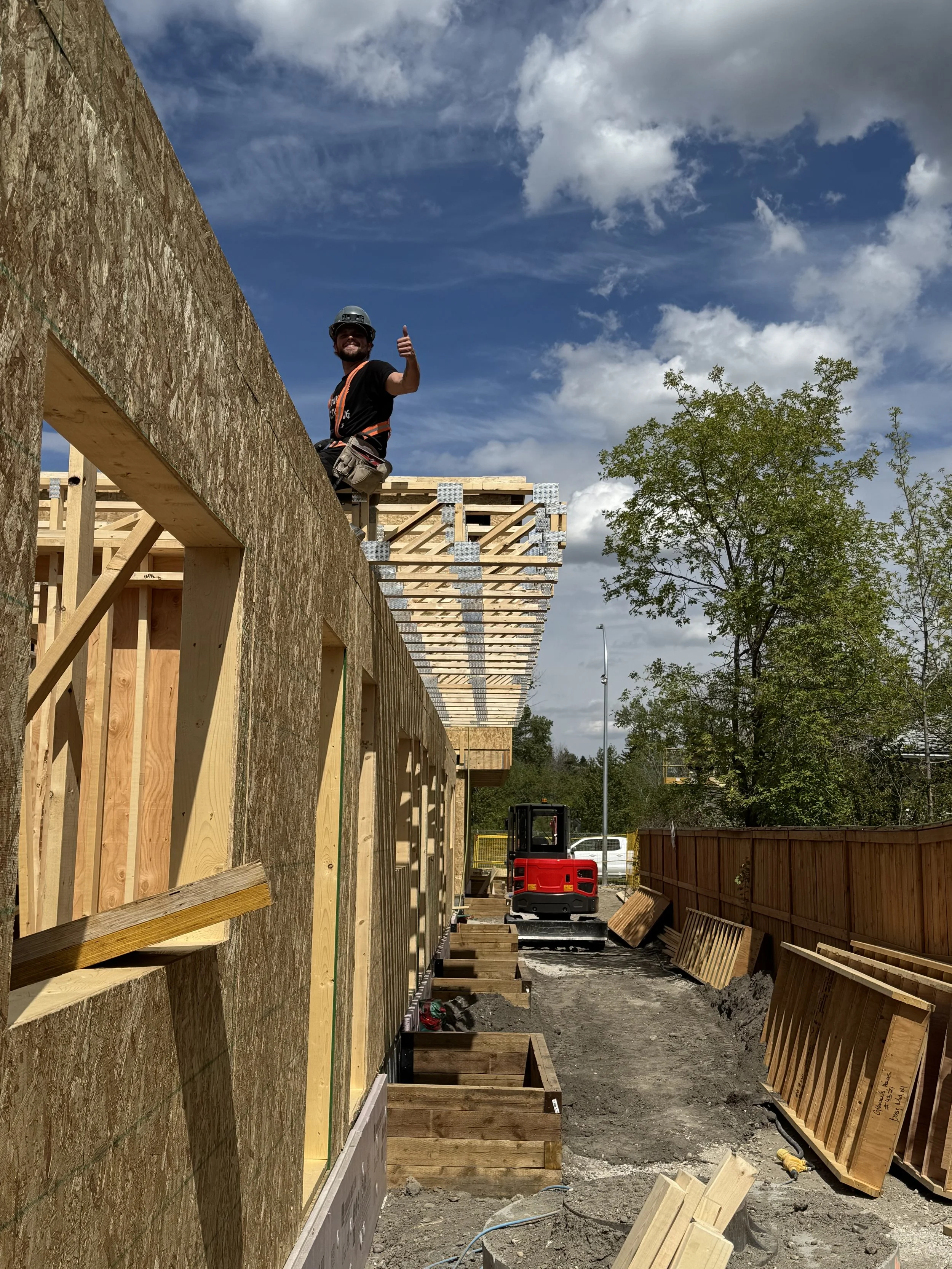 Wood framing of a building under construction with blue sky in the background.