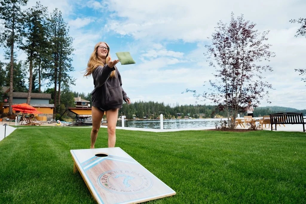 A guest tossing a cornhole bag beside Lake Pend Oreille in Sagle, Idaho