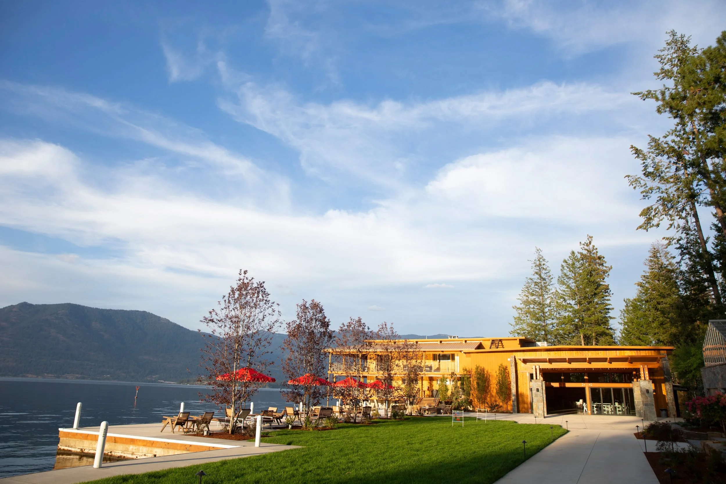 Lounge chairs and red umbrellas on the lakefront at The Retreat on Lake Pend Oreille