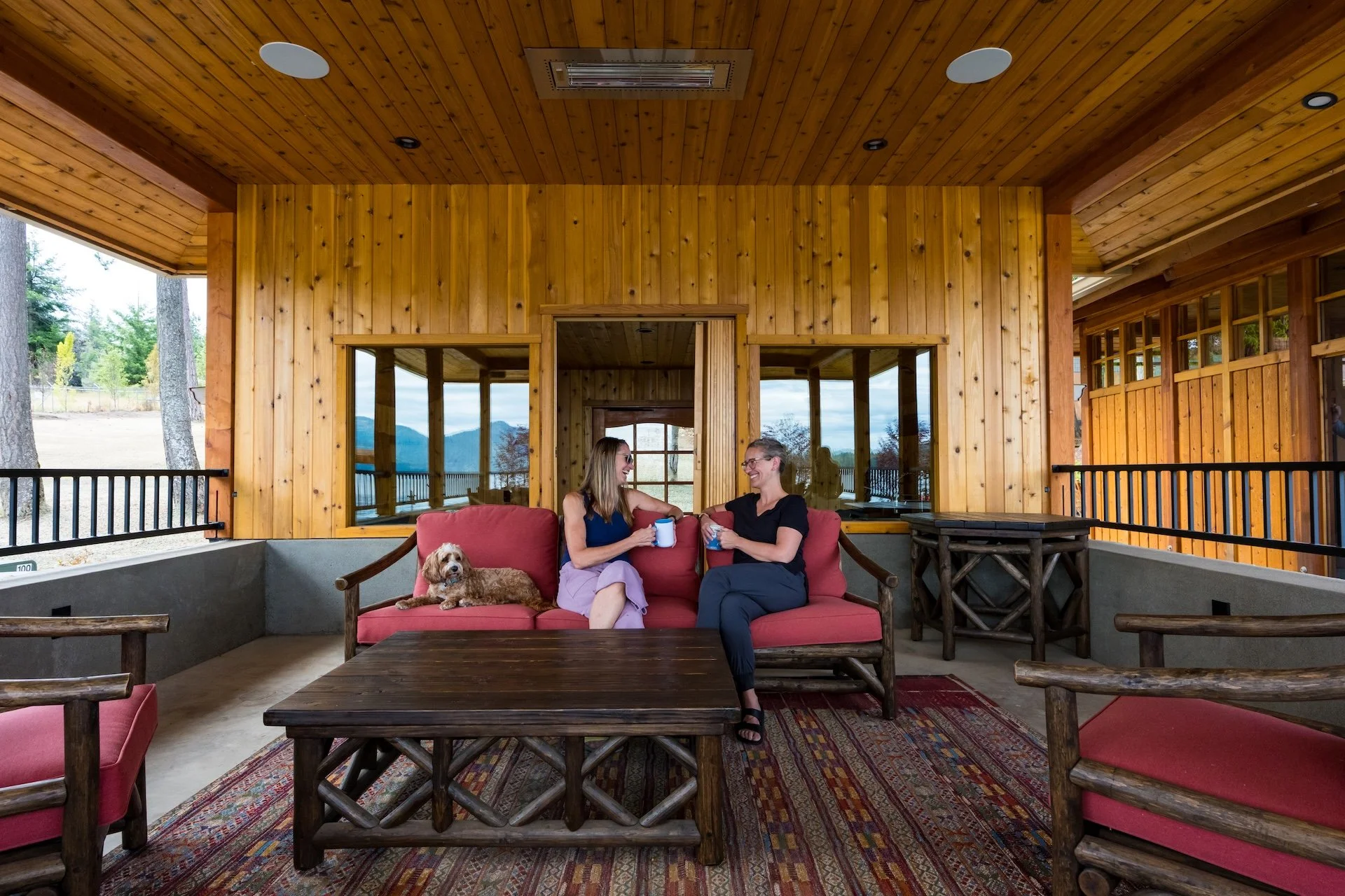Two guests with coffee and a small dog on the patio at The Retreat on Lake Pend Oreille