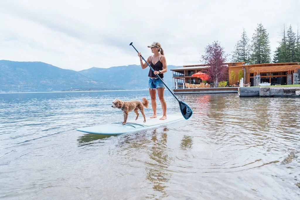 A guest and her golden retriever paddleboarding on Lake Pend Oreille in Sagle, Idaho