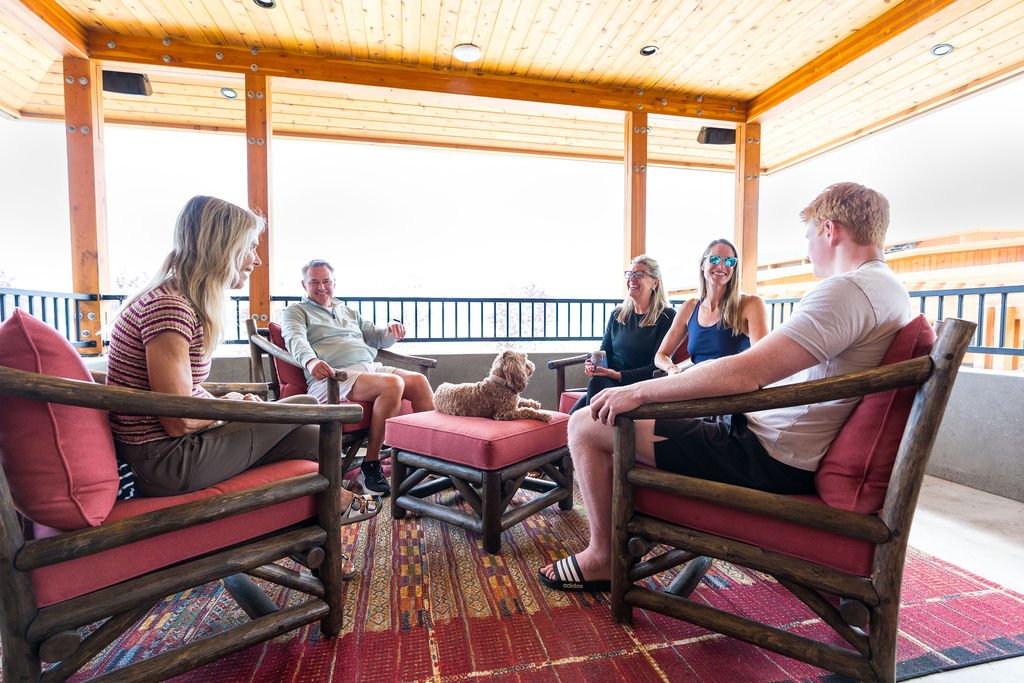 Guests and a dog visiting on the covered deck at The Retreat on Lake Pend Oreille in Sagle, Idaho