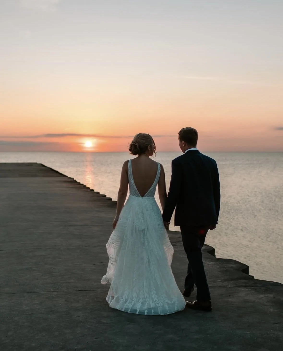 Bride and groom walking hand in hand at sunset at the water's edge on Lake Pend Oreille in Sagle, Idaho