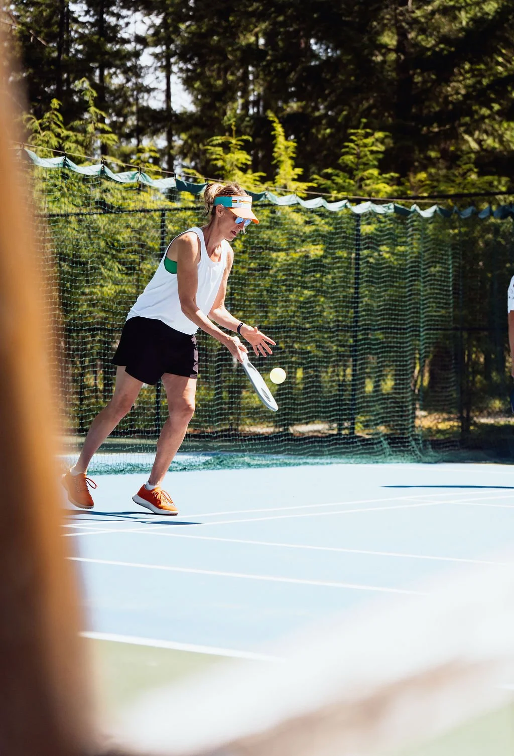 A guest playing pickleball on the tree-lined court at The Retreat on Lake Pend Oreille