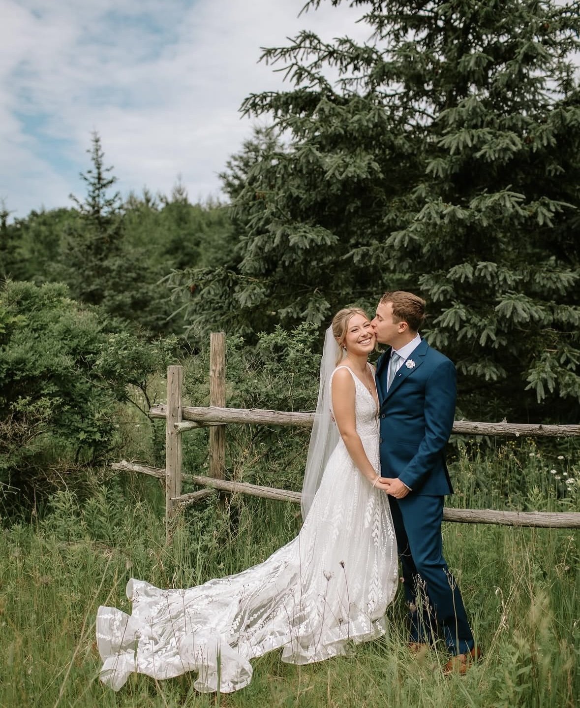 Newlyweds beside the split rail fence in the meadow at The Retreat on Lake Pend Oreille