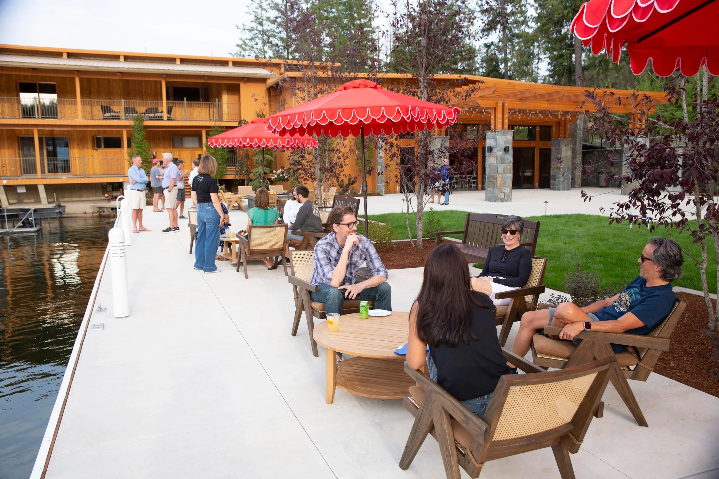 Guests at umbrella tables beside the water at The Retreat on Lake Pend Oreille in Sagle, Idaho