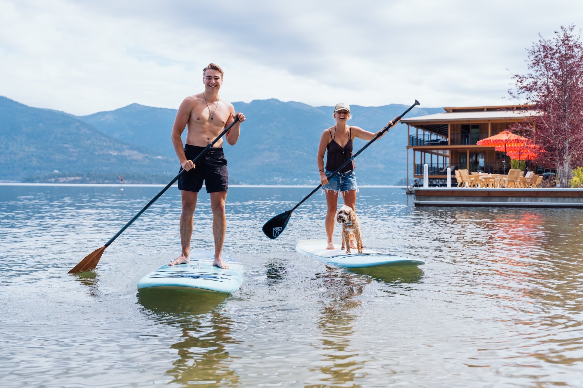 Two guests smiling from their paddleboards on Lake Pend Oreille in Sagle, Idaho