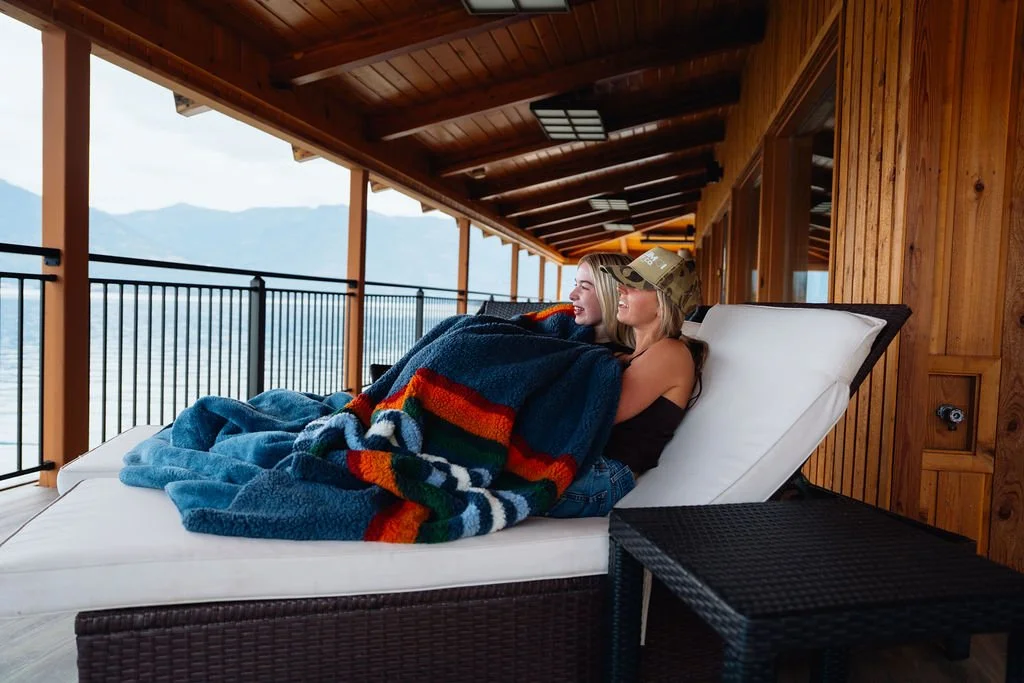 Two guests under a blanket on the covered deck at The Retreat on Lake Pend Oreille