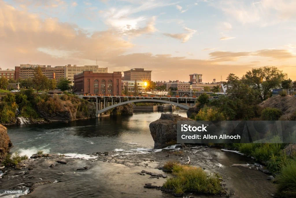 Bridge over a river with city buildings in the background during sunset.