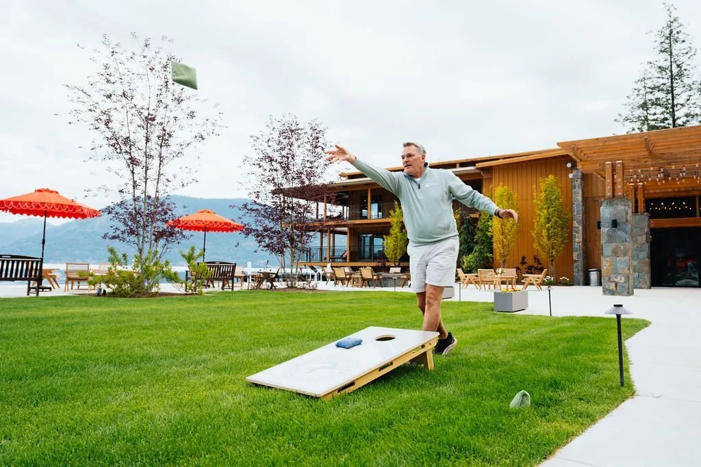 A guest playing cornhole on the lawn above Lake Pend Oreille in Sagle, Idaho