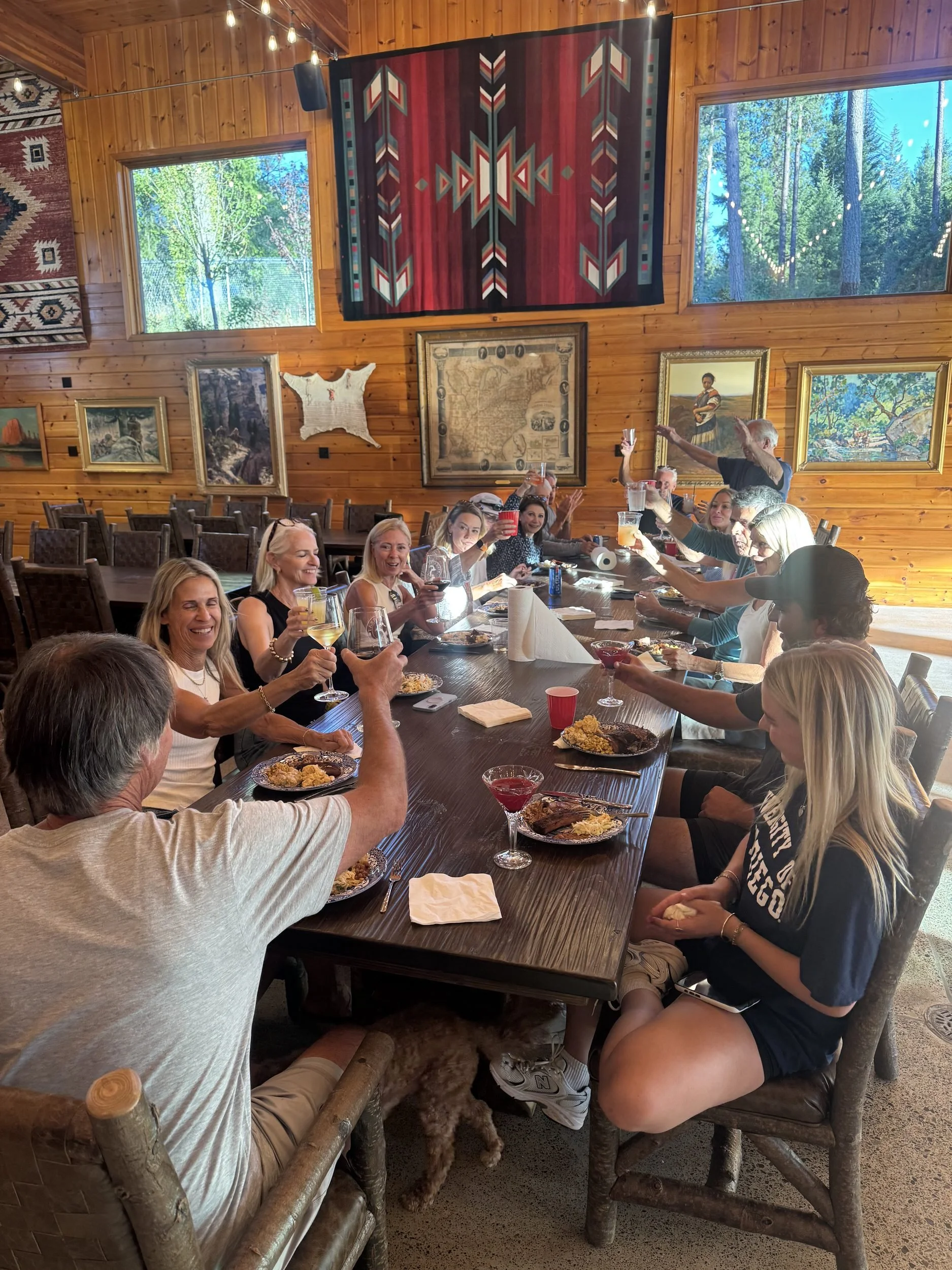 Guests raising a toast around the long dining table in the lodge at The Retreat on Lake Pend Oreille