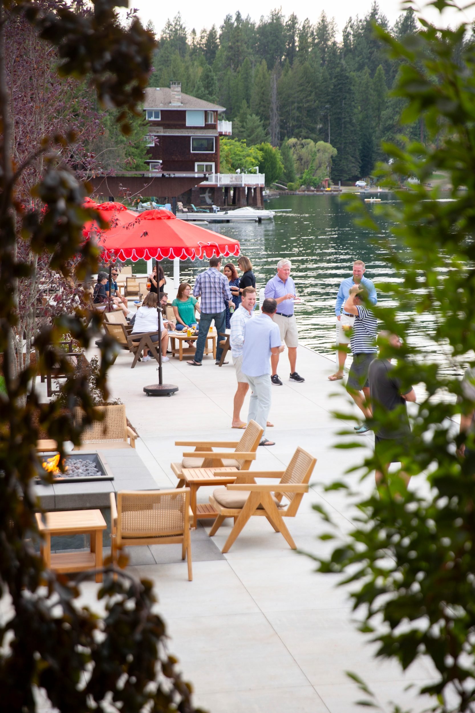 Guests on the lakefront patio under red umbrellas at The Retreat on Lake Pend Oreille