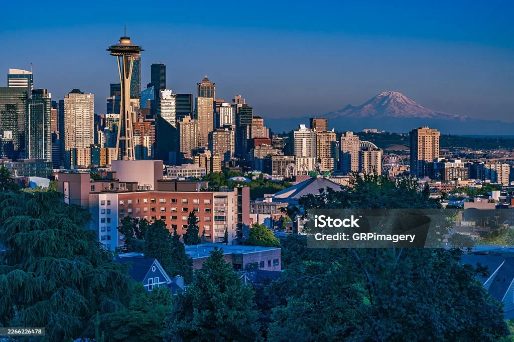 Seattle skyline with the Space Needle in the foreground and Mount Rainier in the background during sunset.