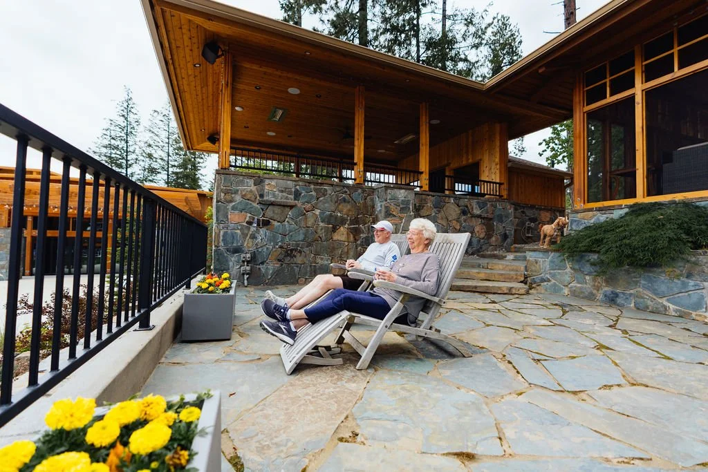 Two guests on lounge chairs on the stone patio outside a cabin at The Retreat on Lake Pend Oreille