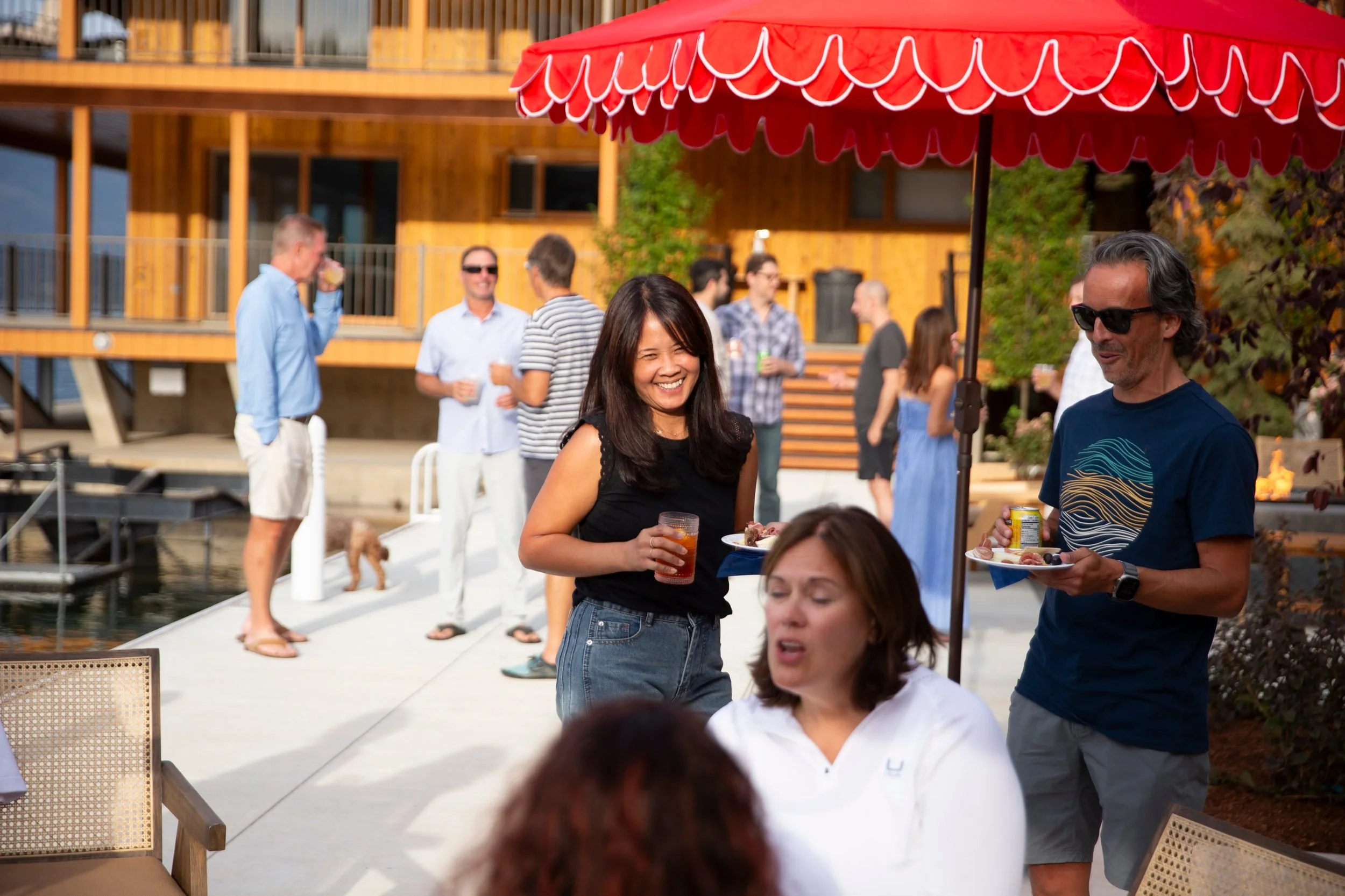 Guests with plates and drinks at a lakeside gathering at The Retreat on Lake Pend Oreille
