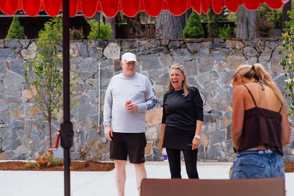 Guests laughing under the red canopy on the patio at The Retreat on Lake Pend Oreille in Sagle, Idaho